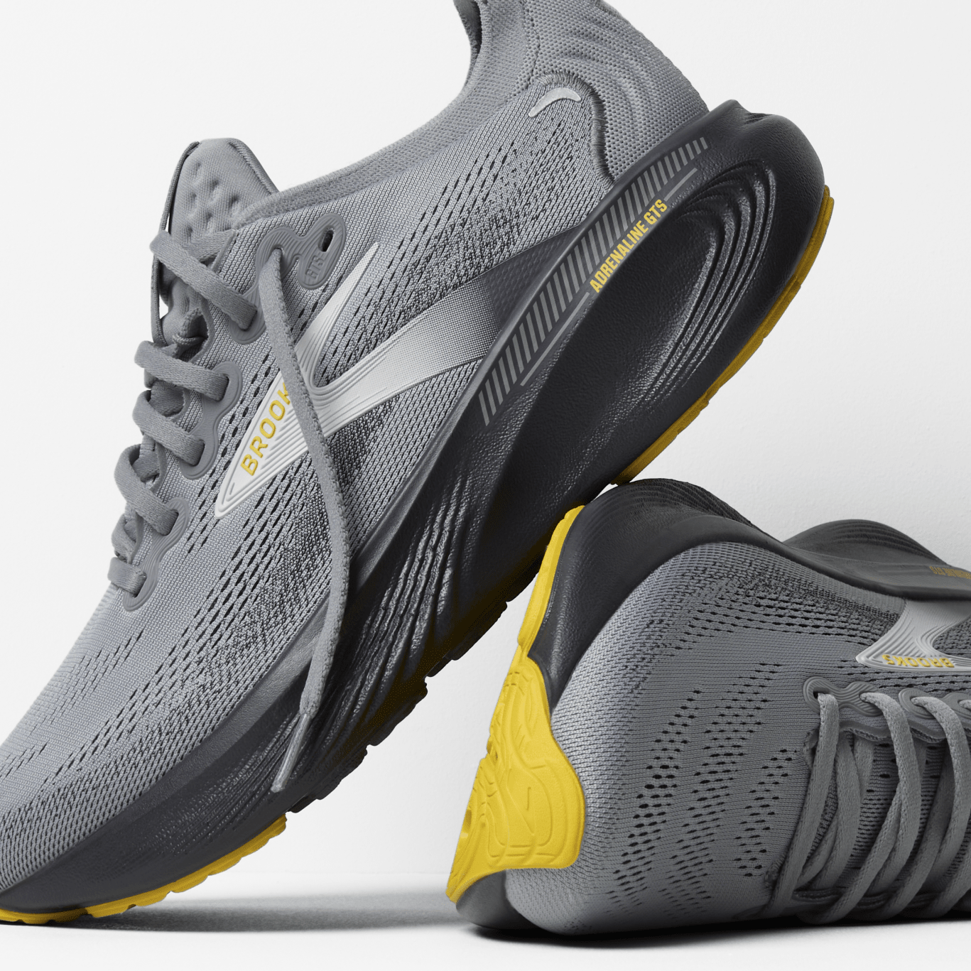 Gray running shoes with yellow accents on a light gray background