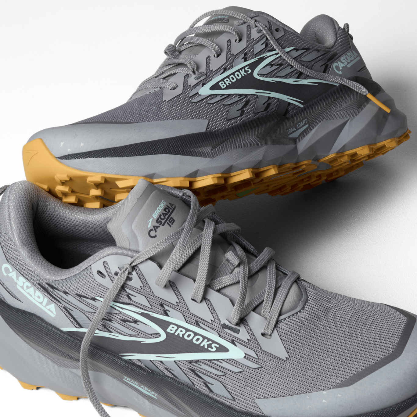 Gray running shoes with yellow soles on a white background