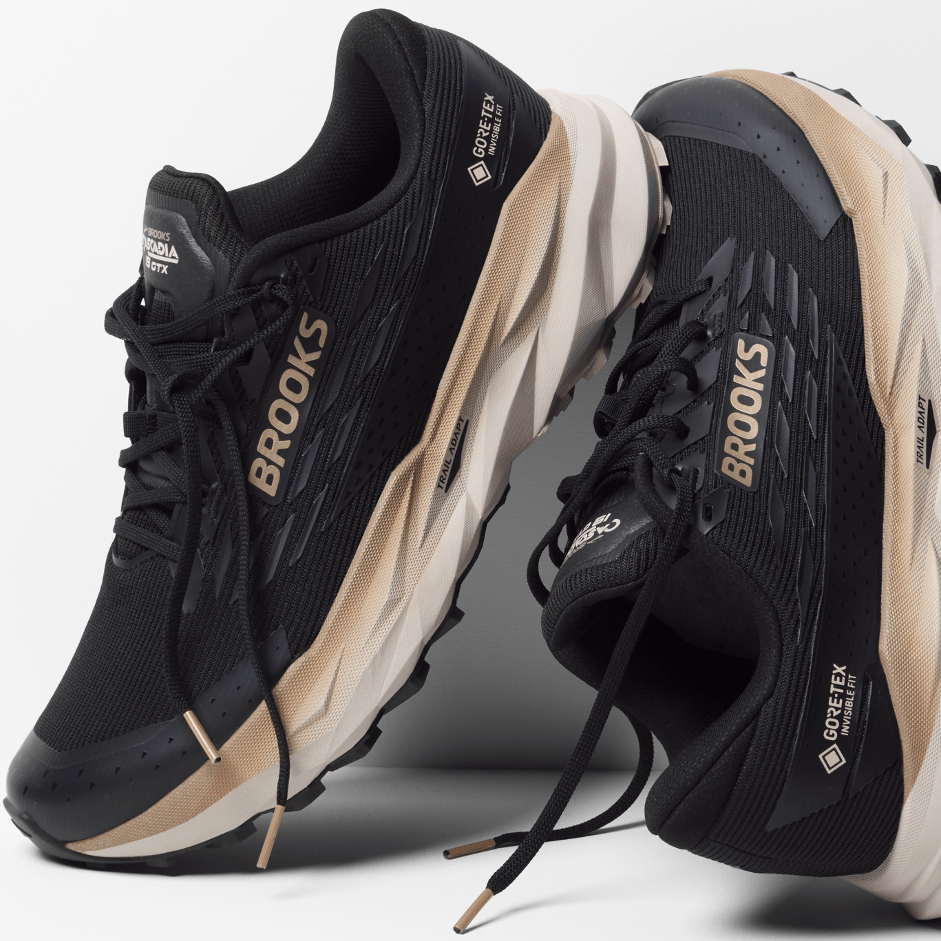 Black and beige running shoes with 'Brooks' branding on a white background