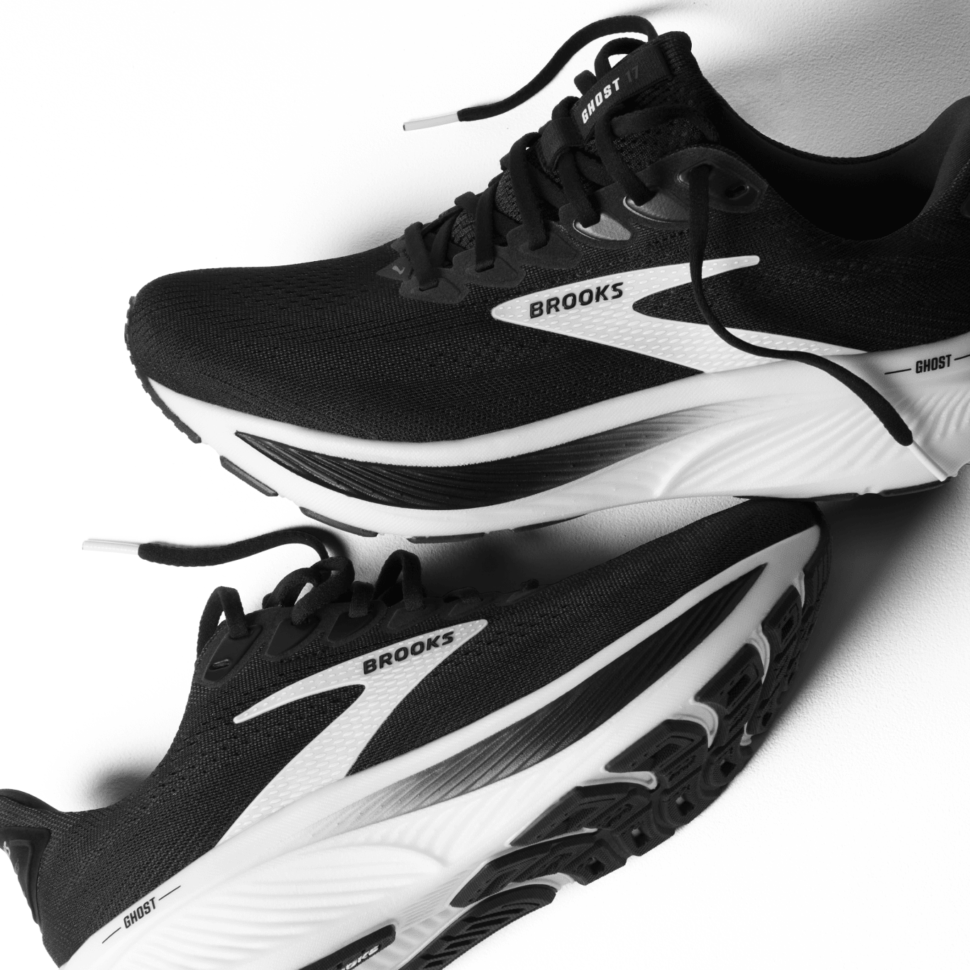 Black and white running shoes with 'Brooks' branding on a light gray background