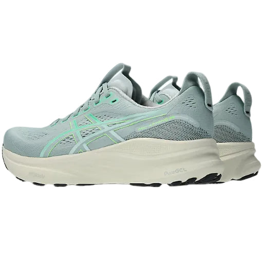 Pair of light blue running shoes with green accents on a white background