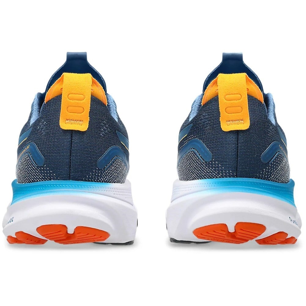 Pair of blue running shoes with orange sole on a white background
