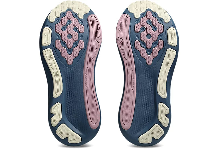 A pair of athletic shoes shown from the sole view, featuring a dark navy blue outsole with pink and cream-colored textured grip patterns.