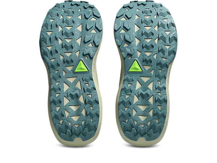 The soles of a pair of trail running shoes, showing a textured teal-green tread pattern with a small bright green triangular logo in the center of each sole, photographed against a solid white background.