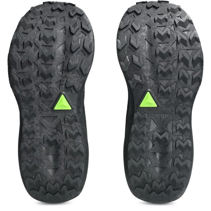 Close-up of black shoe soles with green triangle logos on a white background