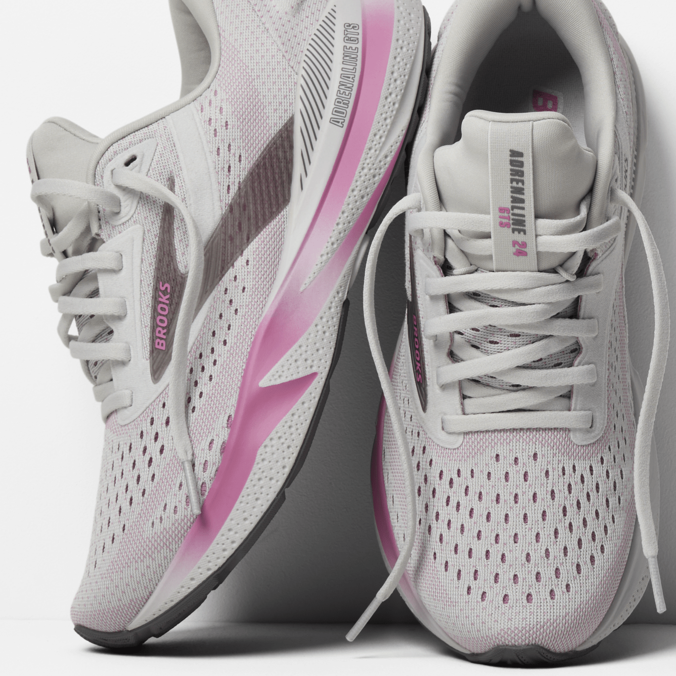 White and pink running shoes with visible branding on a light gray background