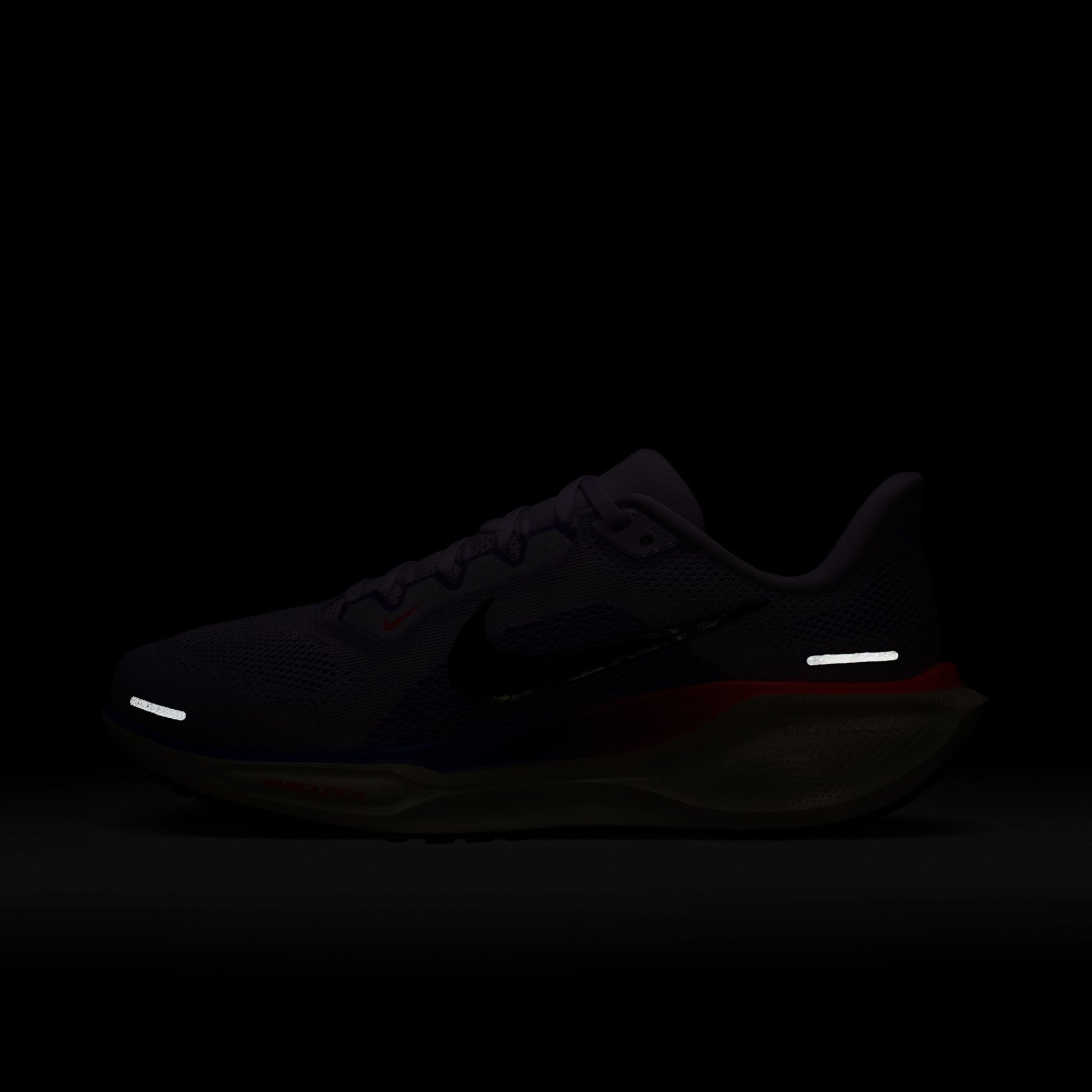 Dark-colored sneaker with reflective elements on a black background