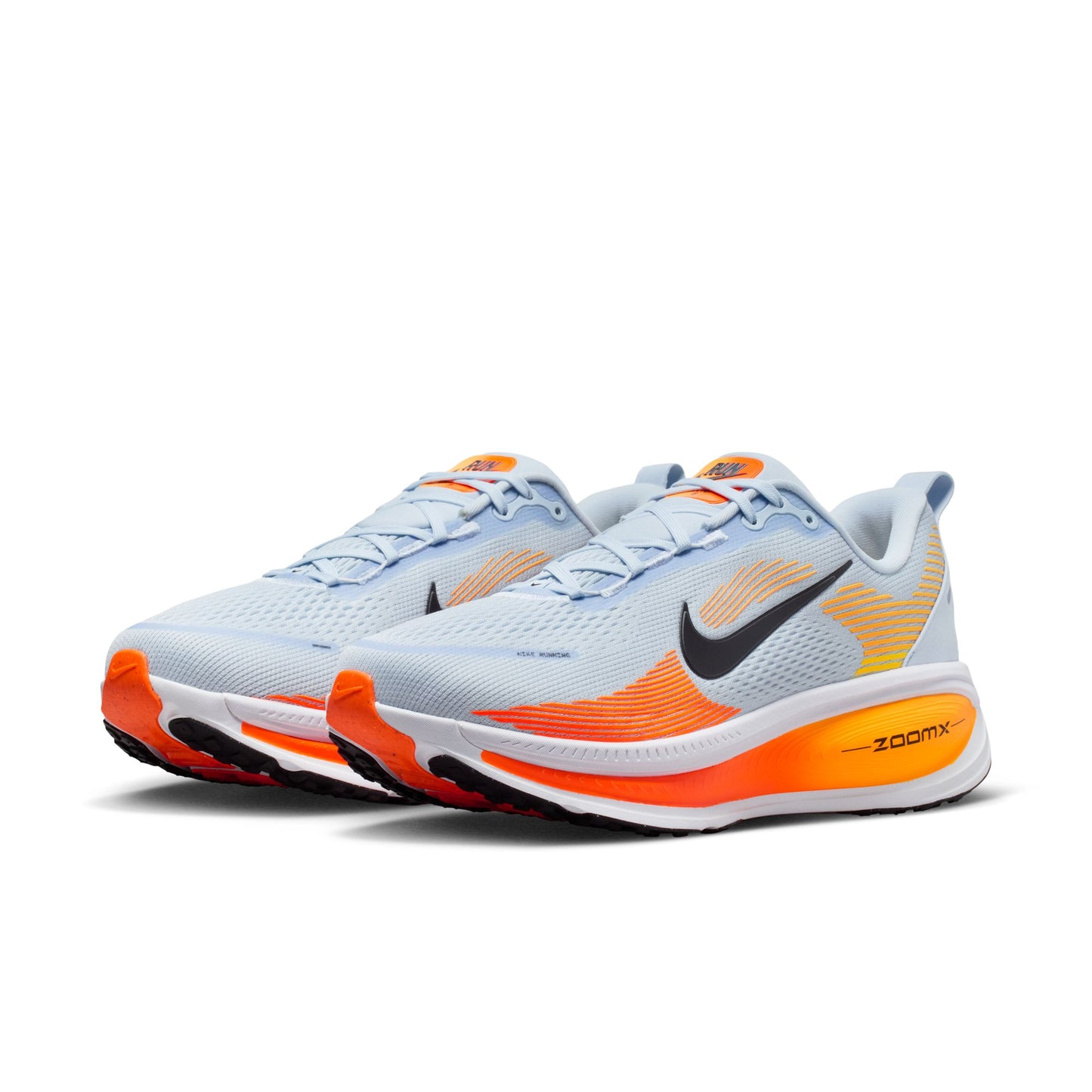 Pair of white and orange running shoes with Nike logo on a white background