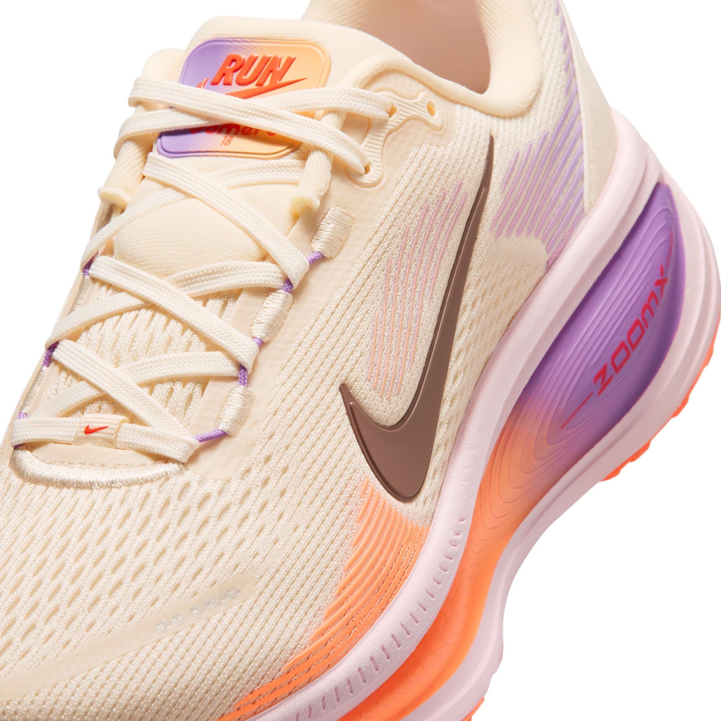 Beige running shoe with purple and orange accents on a white background