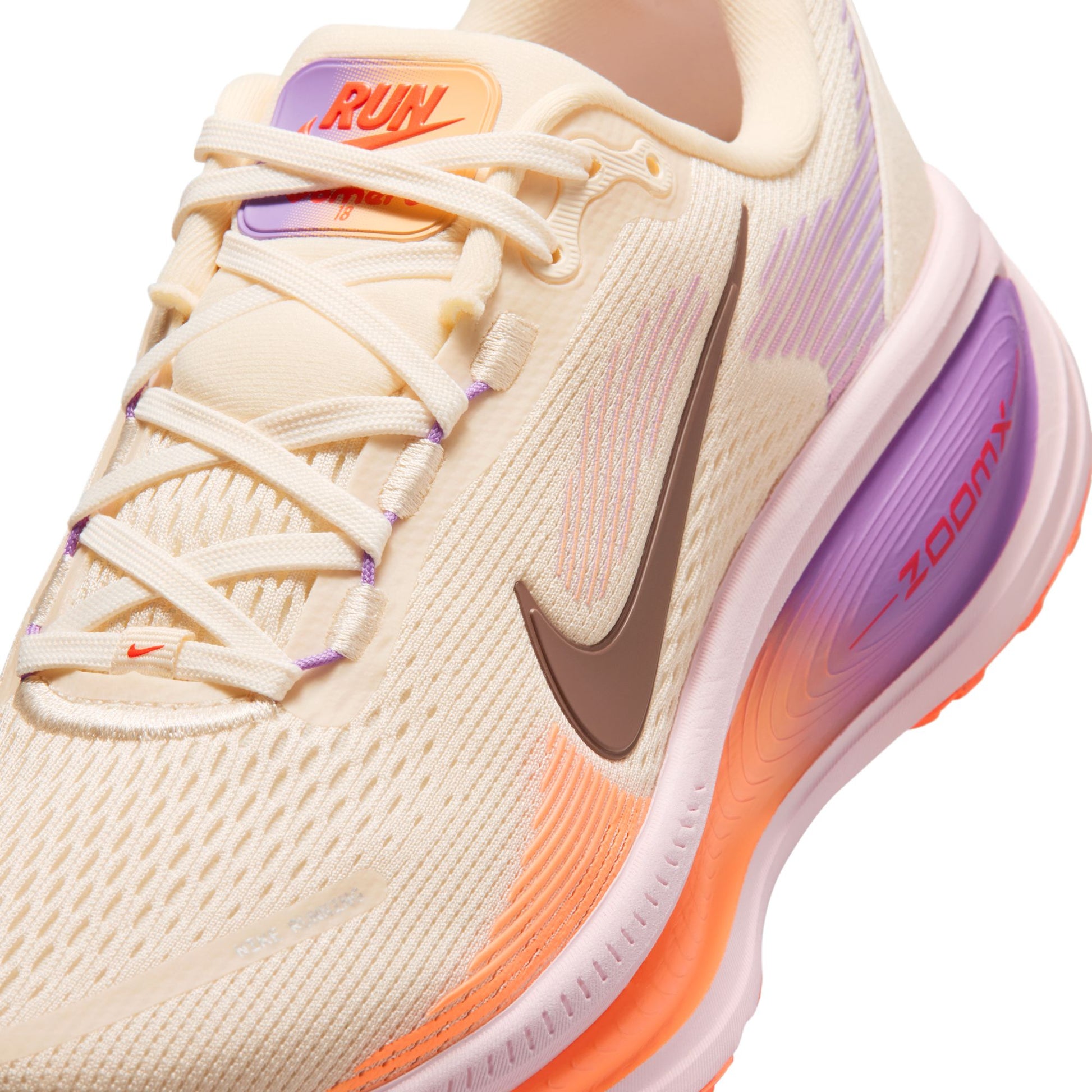 Beige running shoe with purple and orange accents on a white background