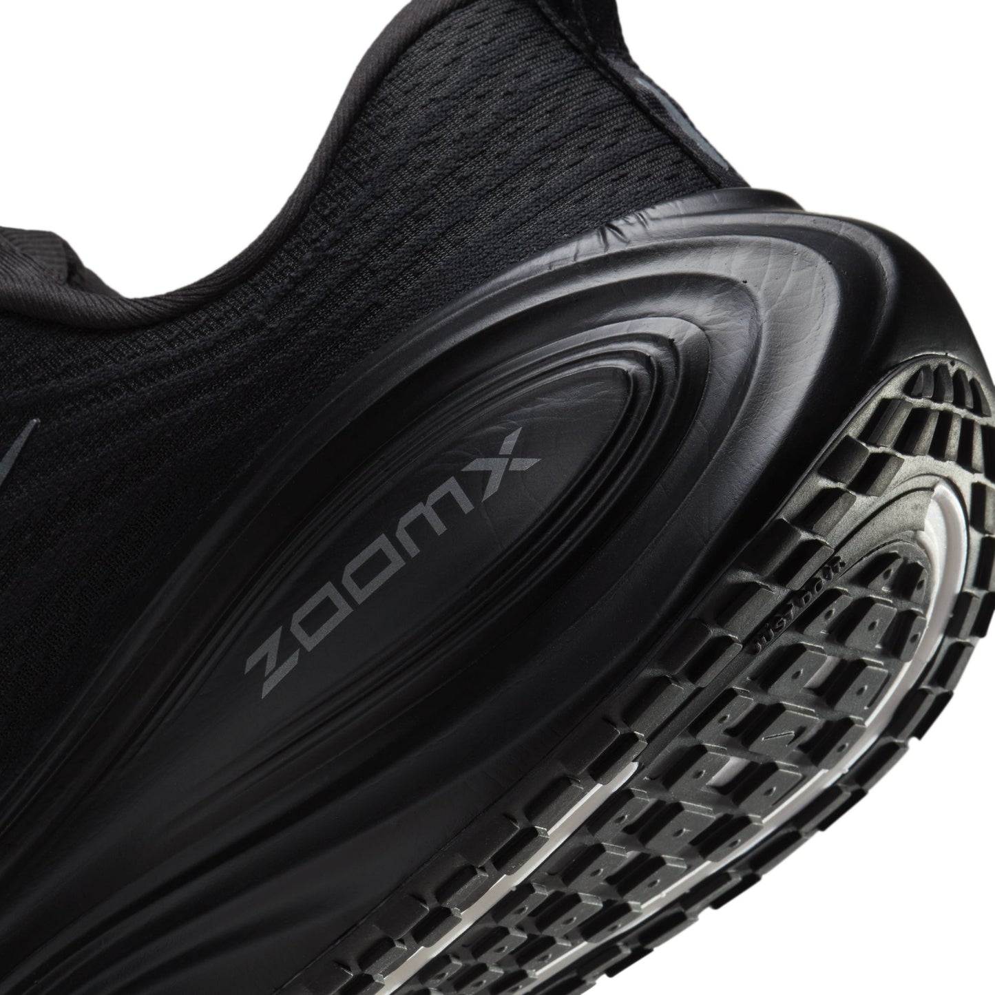Close-up of a black sneaker with 'zoomx' branding on a white background