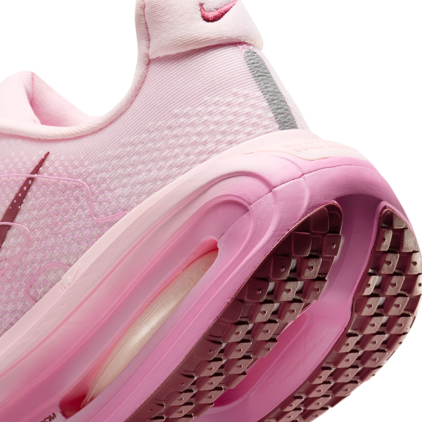 Close-up of a pink sneaker with a focus on the sole and tread pattern.