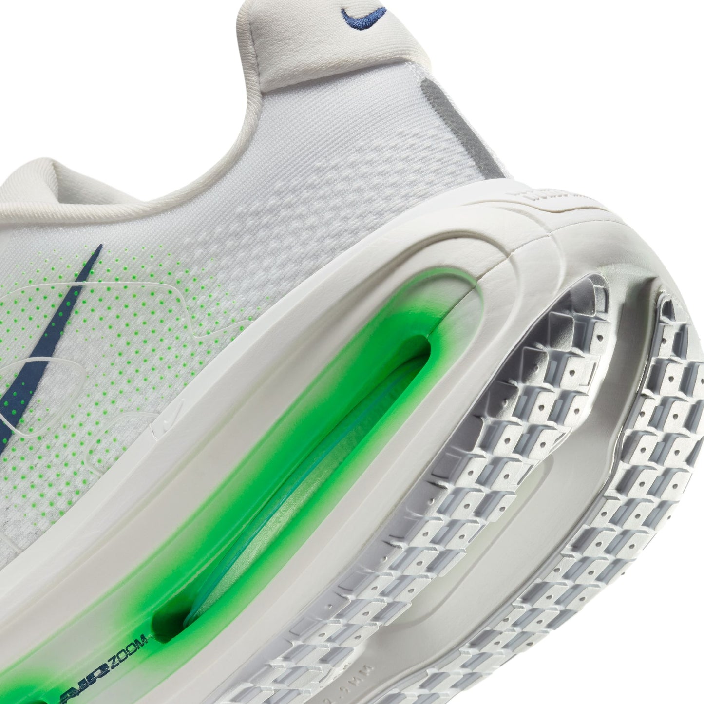 Close-up of a white sneaker with green sole and Nike logo.