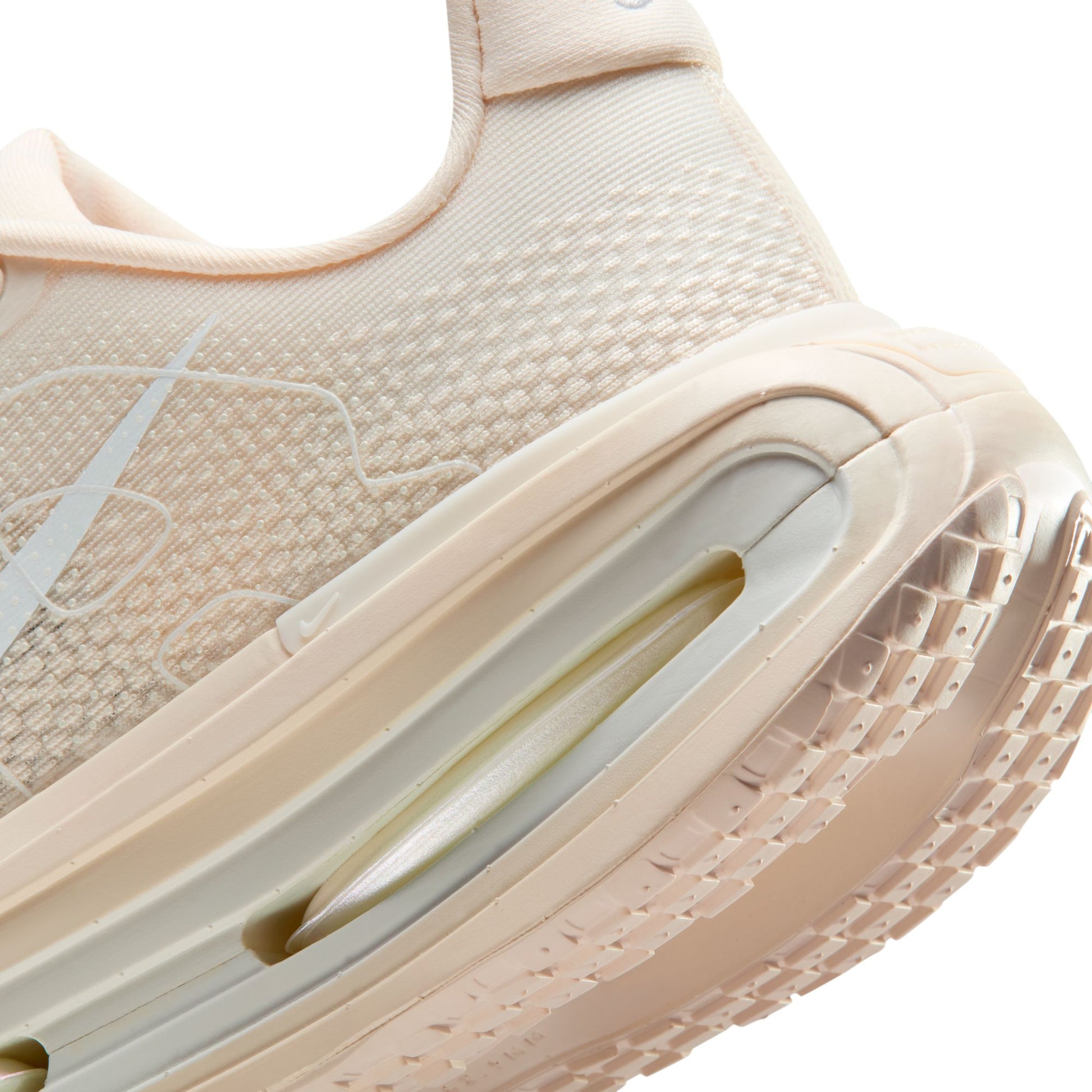 Close-up of a beige sneaker with a brand logo on a white background