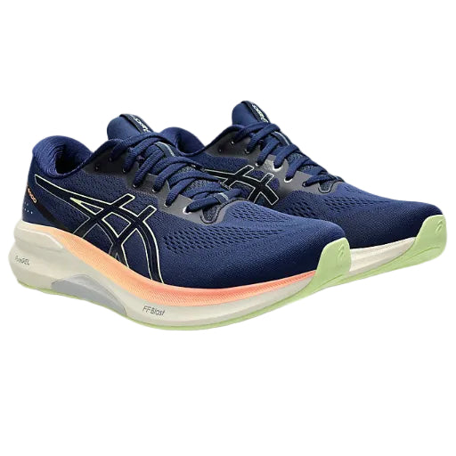 Pair of blue running shoes with green sole on a white background